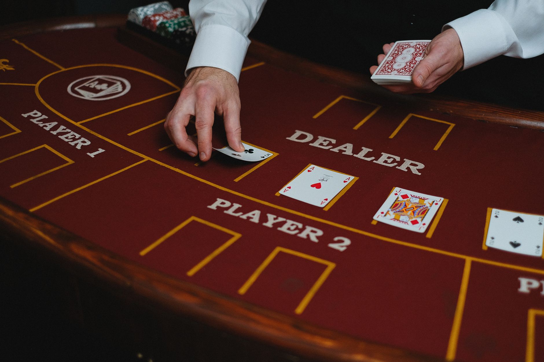 A casino dealer distributes playing cards at a poker table, ready for a game