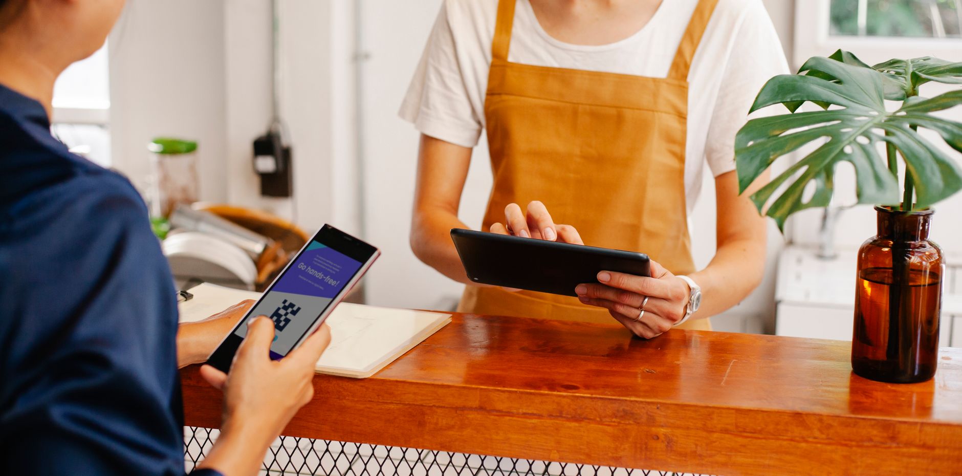 A person holds a phone showing a QR code while another scans it with a card terminal