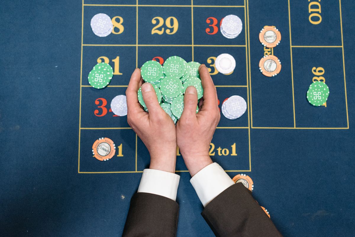 Hands in a suit jacket holding a large pile of green casino chips
